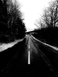 Road along bare trees against clear sky