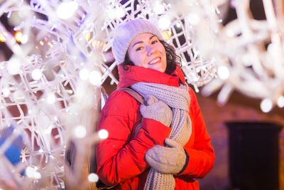 Portrait of smiling woman in illuminated park during winter