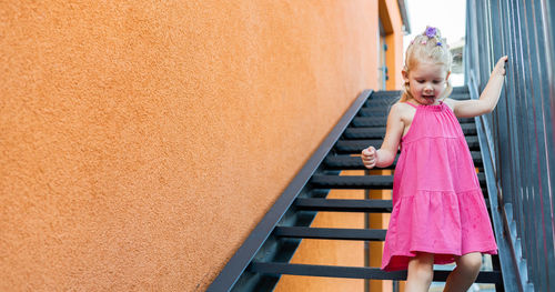 Full length of young woman standing against wall