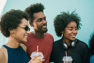 Cheerful friends holding juice while standing outdoors