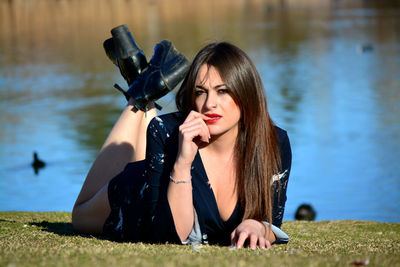 Young woman sitting on grass by lake