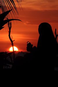 Silhouette man photographing at sunset