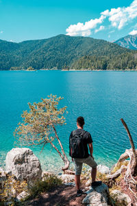 Rear view of woman looking at lake against sky