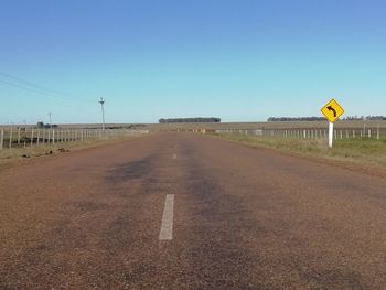 Road sign against clear blue sky