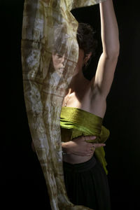 Midsection of woman wearing hat standing against black background
