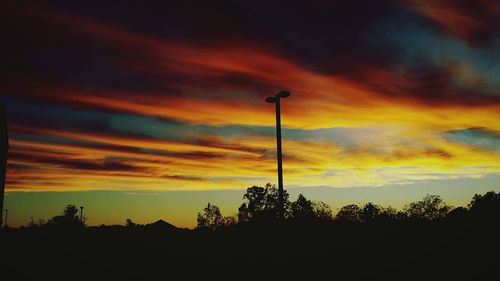 Low angle view of silhouette trees against cloudy sky