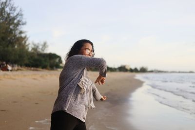 Young woman looking away while standing on beach