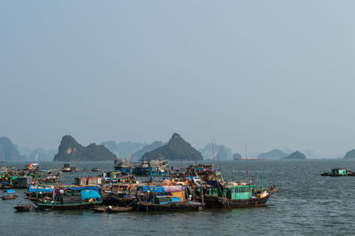 Boats moored in sea against clear sky