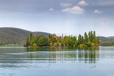 Scenic view of lake by trees against sky