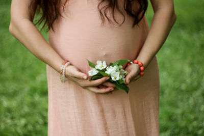 Midsection of woman holding flowering plant