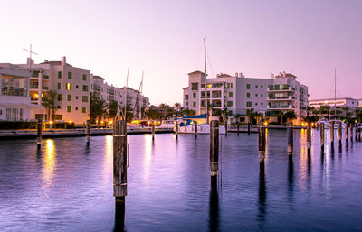 Sailboats in canal by city buildings against sky