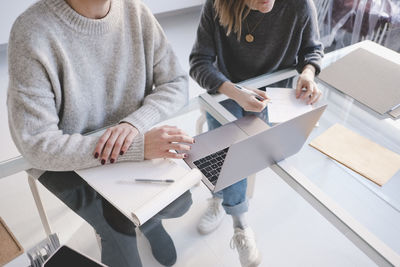 High angle view of female interior designers discussing over laptop at desk in workshop