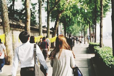 Rear view of people walking on sidewalk