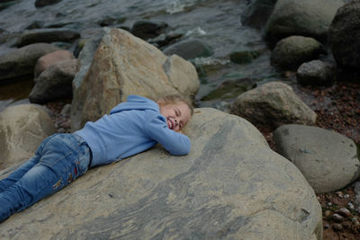 Girl lying down on rock at beach