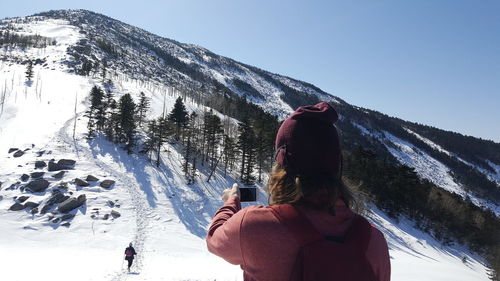 Rear view of woman standing on snow covered mountain