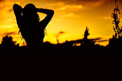 Silhouette woman standing against orange sky