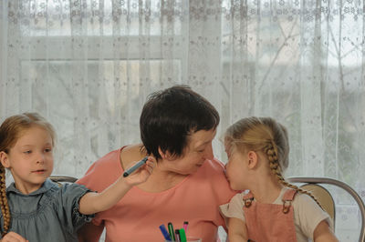 Cute girls sitting with grandmother at home