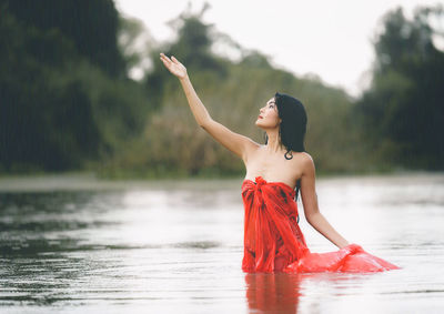 Young woman with arms raised in lake