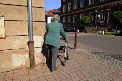 Woman with bicycle on street against building in city