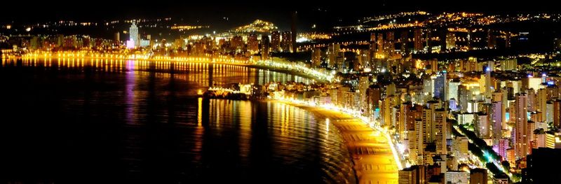 High angle view of illuminated buildings by river at night