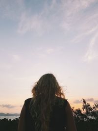 Rear view of woman standing against sky during sunset