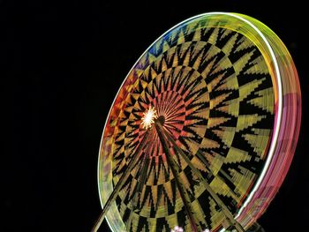 Low angle view of illuminated lighting equipment against black background
