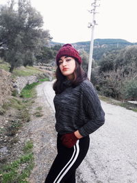 Portrait of young woman standing against trees