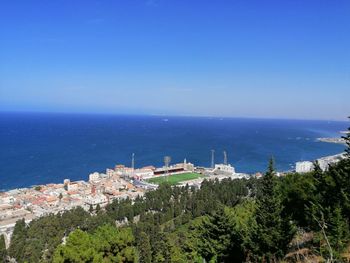 High angle view of townscape by sea against blue sky