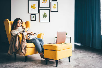 Young woman sitting on sofa at home