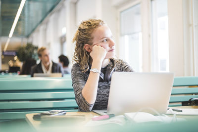 Thoughtful young female student sitting in cafeteria