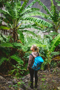 Blond young women with blue backpack admire banana. santo antao island, cape verde