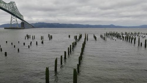 Wooden posts on beach against sky