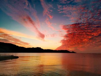 Scenic view of lake against dramatic sky during sunset