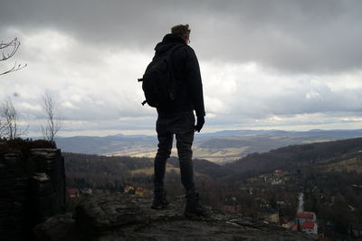 Rear view of man standing on mountain against sky