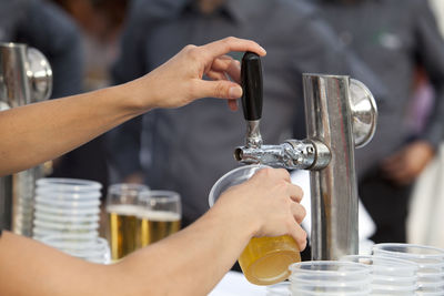 Cropped hands of woman filling glass with beer