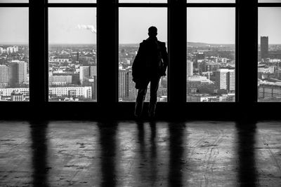 Rear view of man looking at city through window