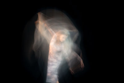 Blurred motion of man standing against black background