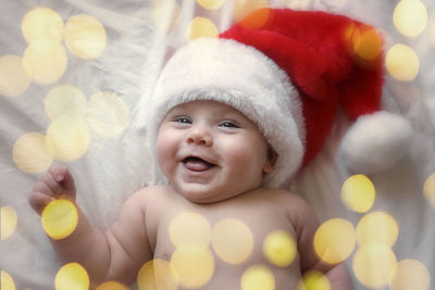 Smiling baby wearing red santa claus hat celebrating christmas. cute newborn baby in christmas hat