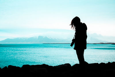 Silhouette woman standing by sea against sky