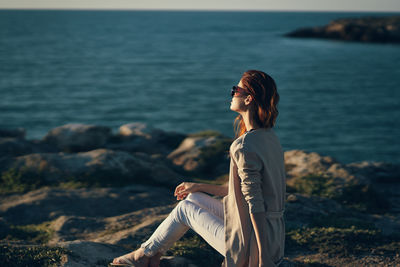 Side view of young woman sitting on land