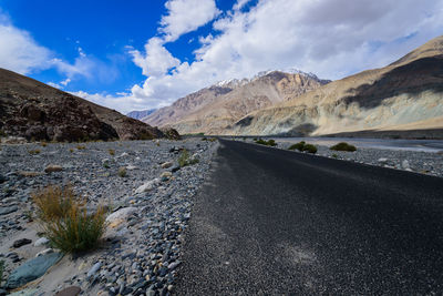 Road by mountains against sky