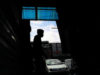 Silhouette man standing by car window
