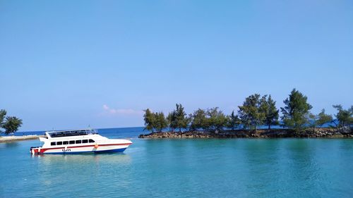 Boat sailing in sea against clear blue sky