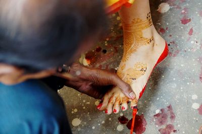 Close-up of woman applying red nail polish to bride