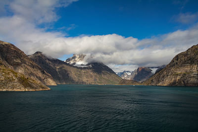 Scenic view of sea by mountains against sky