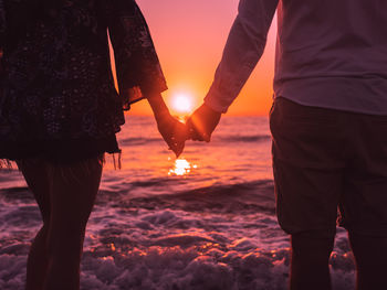 Couple hands at sunset on beach