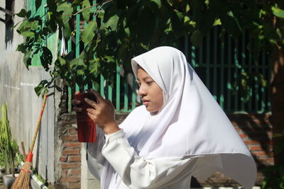 Portrait of young woman standing against plants