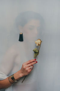 Digital composite image of woman holding wilted flower