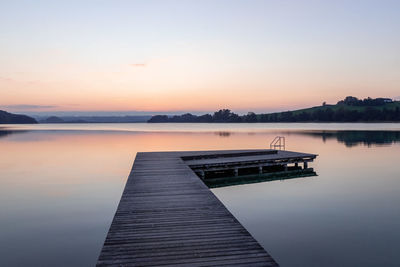 Pier on lake against sky during sunset