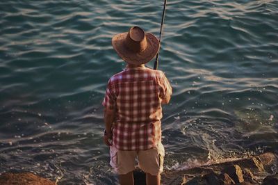 Rear view of man standing by sea